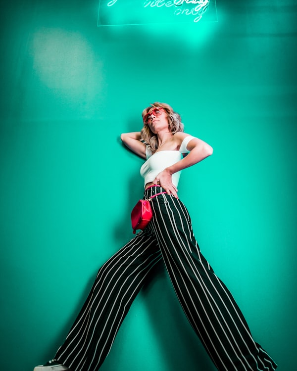 Model posing against a green wall in striped trousers